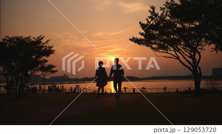 夕暮れの湖畔を歩くふたり 129053720