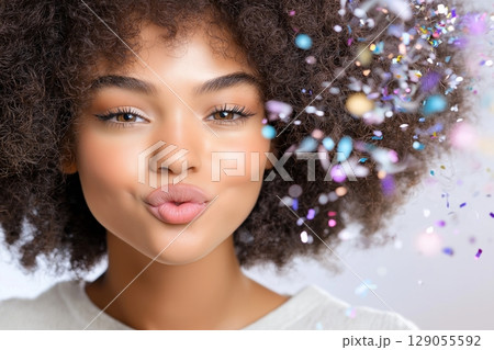 Close-up shot of a person with textured curly hair and colorful confetti falling around. 129055592