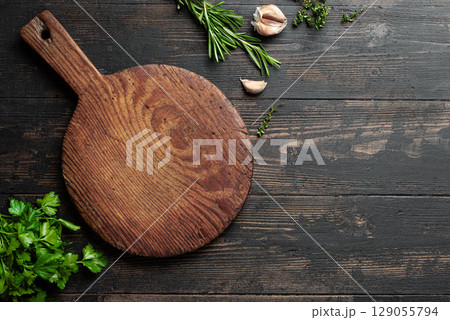 Empty wooden round platter with herbs and garlic Empty wooden round platter with herbs and garlic 129055794