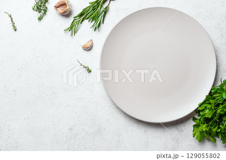 Empty white ceramic plate with herbs and garlic Empty white ceramic plate with herbs and garlic 129055802