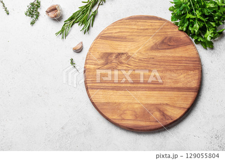 Empty wooden round platter with herbs and garlic Empty wooden round platter with herbs and garlic 129055804