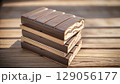Stack of Premium Dark Chocolate Bars with Milk Chocolate Layers on Wooden Background 129056177