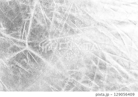 Worn scratched silver foil material with folds and wrinkles. Abstract light gray background Worn scratched silver foil material with folds and wrinkles. Abstract light gray background 129056409