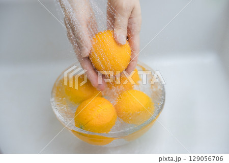 オレンジを洗う女性 129056706