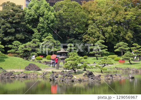 旧芝離宮恩賜庭園の池に映る和傘と石灯籠、松が並ぶ日本庭園の風景 旧芝離宮恩賜庭園の池に映る和傘と石灯籠、松が並ぶ日本庭園の風景 129056967