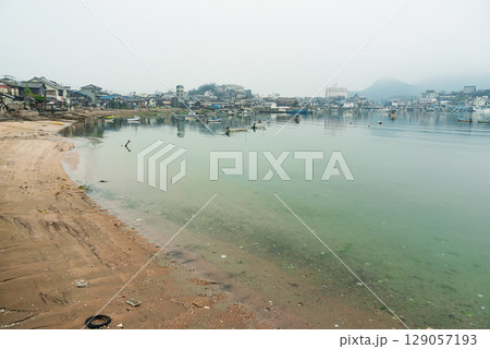 鞆の浦・穏やかな瀬戸内海と砂浜、歴史的な港町の町並みを望む全景 鞆の浦・穏やかな瀬戸内海と砂浜、歴史的な港町の町並みを望む全景 129057193
