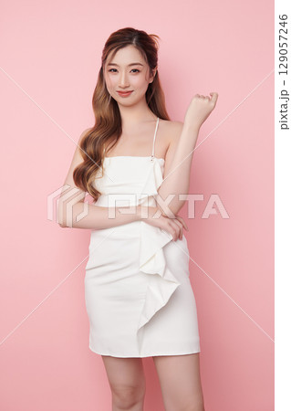 Beautiful face of young Asian woman in sexy dress white Perfect slim body on pink background, plastic surgery and aesthetic cosmetology, Facial and skin care concept 129057246