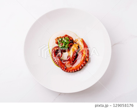 Deliciously cooked octopus served elegantly on a white plate with garnishing 129058176