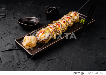 Delicious sushi rolls served on a dark platter with dipping sauces Delicious sushi rolls served on a dark platter with dipping sauces 129058182