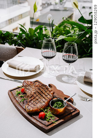 Steak dinner with red wine and fresh herbs in outdoor garden setting Steak dinner with red wine and fresh herbs in outdoor garden setting 129058269