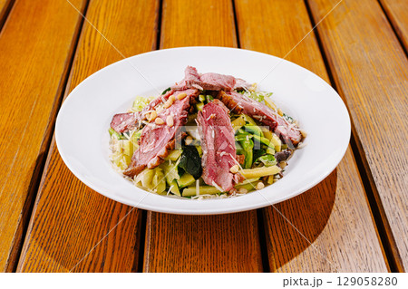 Fresh salad with grilled meat served on a wooden table outdoors Fresh salad with grilled meat served on a wooden table outdoors 129058280