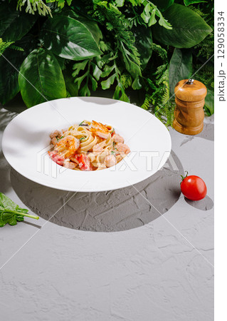 Fresh pasta dish with vegetables served on a white plate in a natural setting Fresh pasta dish with vegetables served on a white plate in a natural setting 129058334