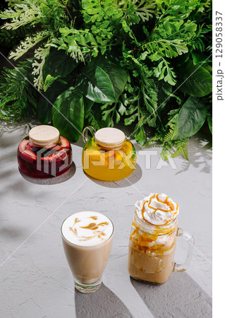 Colorful beverages displayed on a table surrounded by lush greenery 129058337