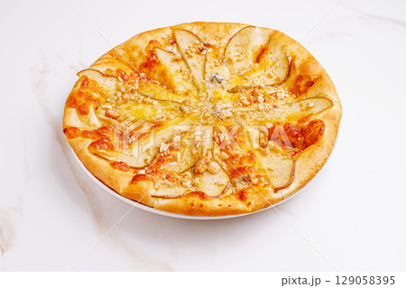 Creative pear and cheese pizza topped with nuts and honey drizzle 129058395