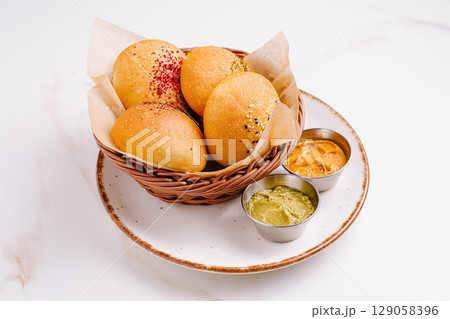 Freshly made bread rolls served with flavorful dips on a plate Freshly made bread rolls served with flavorful dips on a plate 129058396