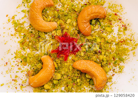 Cashews and pistachios arranged on a decorative plate with red accents 129058420