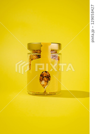 Bright yellow jar filled with granola on a contrasting background 129058427