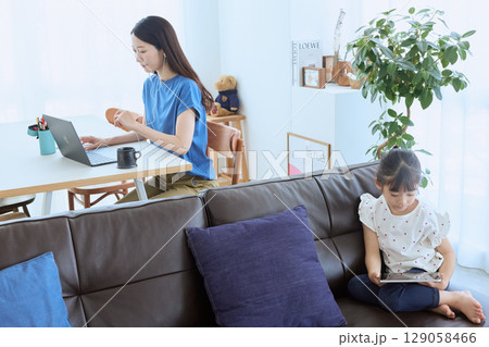 在宅勤務する母親とタブレットを楽しむ子ども 129058466