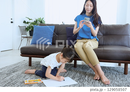 子どもがお絵かきをする横でスマートフォンを 129058507