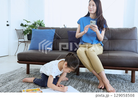 子どもがお絵かきをする横でスマートフォンを 129058508