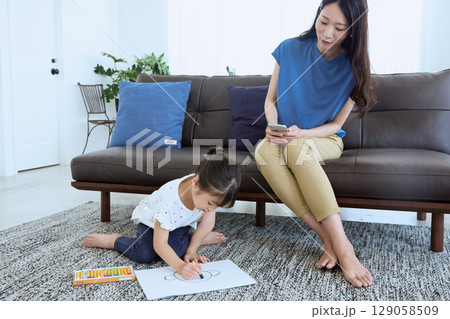 子どもがお絵かきをする横でスマートフォンを 129058509