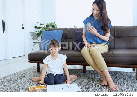 子どもがお絵かきをする横でスマートフォンを 129058513