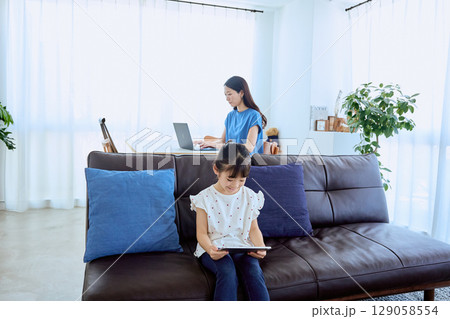 在宅勤務する母親とタブレットを楽しむ子ども 129058554