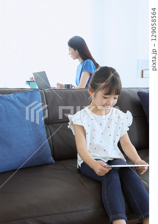 在宅勤務する母親とタブレットを楽しむ子ども 129058564