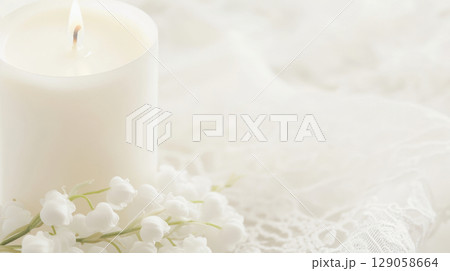 White ceremonial candle surrounded by delicate lilies of the valley flowers, symbol of christening 129058664