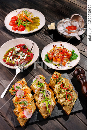 Delicious variety of gourmet appetizers served on rustic wooden table Delicious variety of gourmet appetizers served on rustic wooden table 129058699