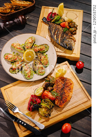 Grilled seafood and veggies on wooden platters at a restaurant 129058702