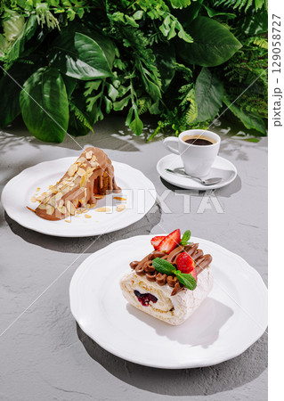 Delicious desserts served on plates with coffee in a lush green setting 129058727