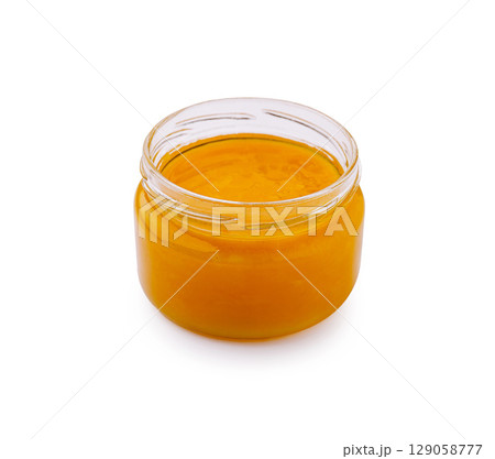 Bright golden honey jar in a clear glass container on a white background Bright golden honey jar in a clear glass container on a white background 129058777