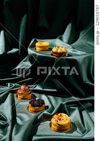 Elegant dessert display featuring various pastries on green fabric 129058787