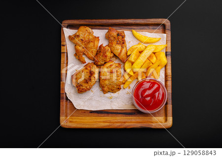 Crispy fried chicken with golden fries on a wooden tray Crispy fried chicken with golden fries on a wooden tray 129058843