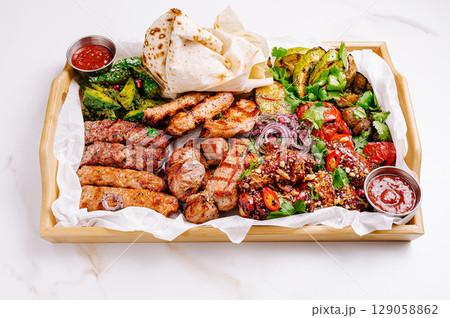 Delicious meat platter featuring various grilled dishes served with sauces 129058862