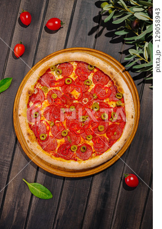 Delicious pepperoni pizza topped with green olives and fresh ingredients 129058943