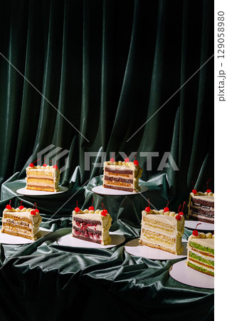 Colorful layered cakes displayed elegantly on fabric background 129058980