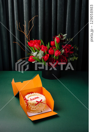 Celebrating with a cake and red flower bouquet on a green table 129058983