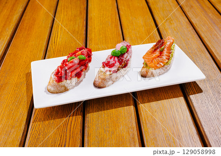 Delicious tapas served on a white plate in a cozy restaurant at sunset 129058998