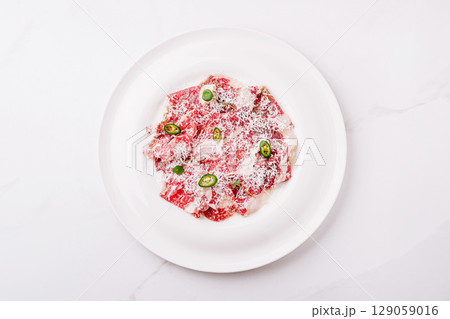 Spicy Beef Carpaccio with Parmesan and Green Chili on white plate 129059016