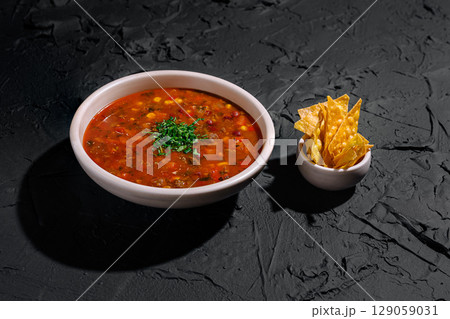 Delicious bowl of spicy soup with fresh toppings and crispy tortilla chips Delicious bowl of spicy soup with fresh toppings and crispy tortilla chips 129059031
