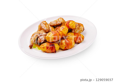Juicy grilled chicken with bacon-wrapped potatoes on a white plate Juicy grilled chicken with bacon-wrapped potatoes on a white plate 129059037