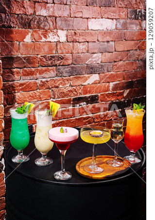 Colorful cocktails displayed on a table against a rustic brick wall Colorful cocktails displayed on a table against a rustic brick wall 129059207