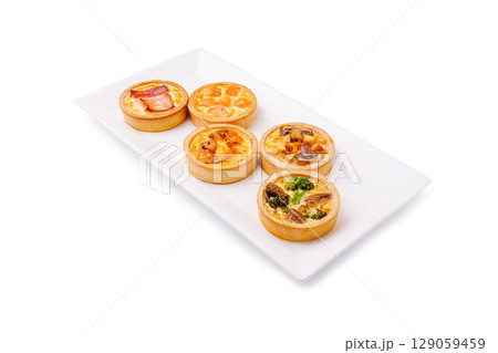 Delicious array of savory tarts displayed on a white serving platter 129059459