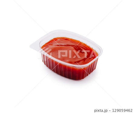 Bright red condiment in a small plastic container for savory dishes Bright red condiment in a small plastic container for savory dishes 129059462