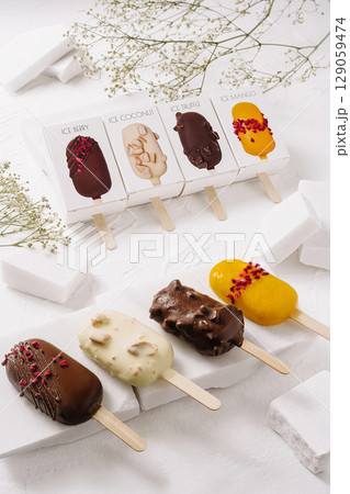 Variety of ice pops displayed on a white table with decorative elements 129059474