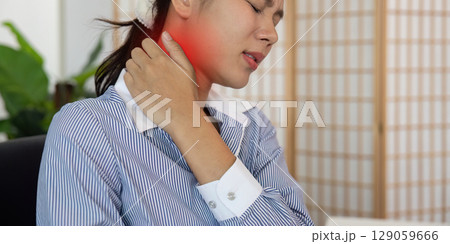 Office Syndrome: Young woman grimacing in pain while working at her desk 129059666