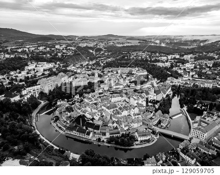 A breathtaking sunrise casts warm light over the historic town of Cesky Krumlov, highlighting its unique architecture and the meandering Vltava River. 129059705