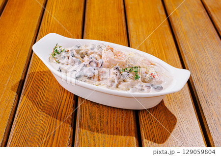 Gourmet seafood dish served in white ceramic bowl on wooden table Gourmet seafood dish served in white ceramic bowl on wooden table 129059804